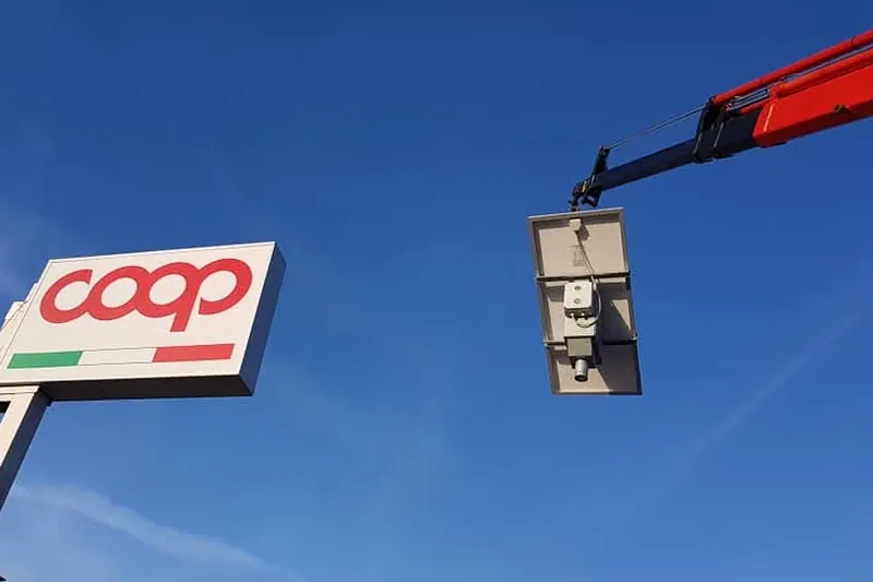 Insegna Coop su palo durante il montaggio con la gru