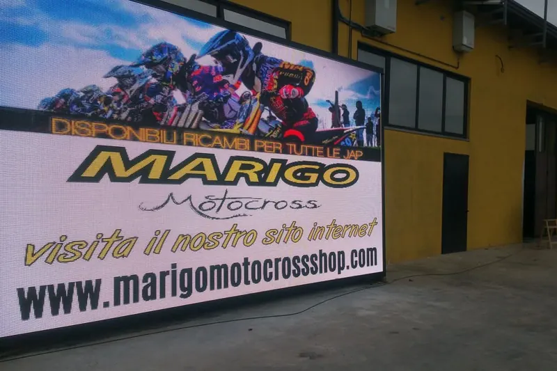 Ledwall acceso MARIGO Motocross su un capannone giallo