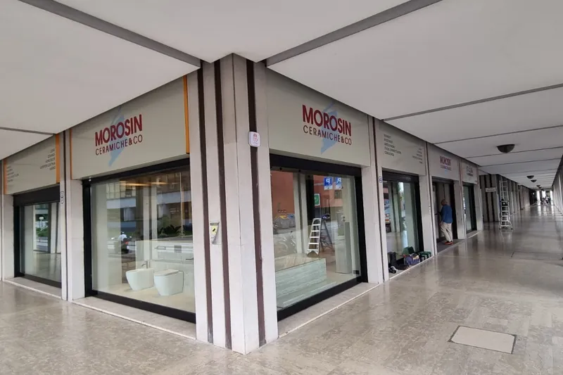 Insegne MOROSIN Ceramiche & Co sopra le vetrine, sotto i portici