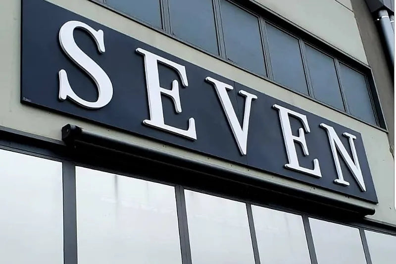 Lettere SEVEN in rilievo su una fascia nera in facciata